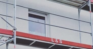 fassade_nachher Fassadenreinigung in vollem Gange – Ein Reinigungsteam verwendet Hochdruckreiniger, um die Außenwand eines Gebäudes zu säubern.
